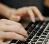 hands typing on a laptop keyboard
